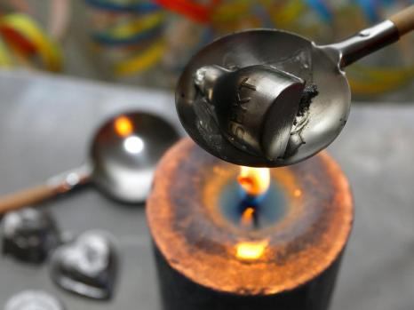 Melting tin or lead or pewter in a ladle over a candle flame